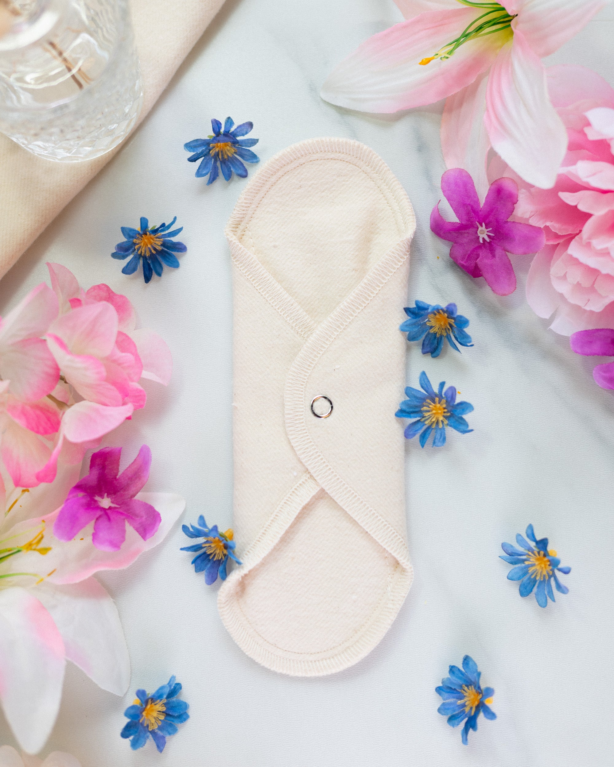 Reusable cloth pad in white organic cotton with small blue and pink flowers around it