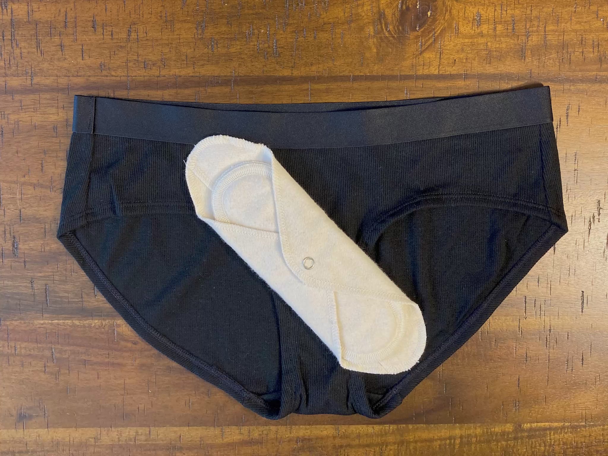 Load video: Stop motion video showing how to snap a reusable cloth pad into your underwear